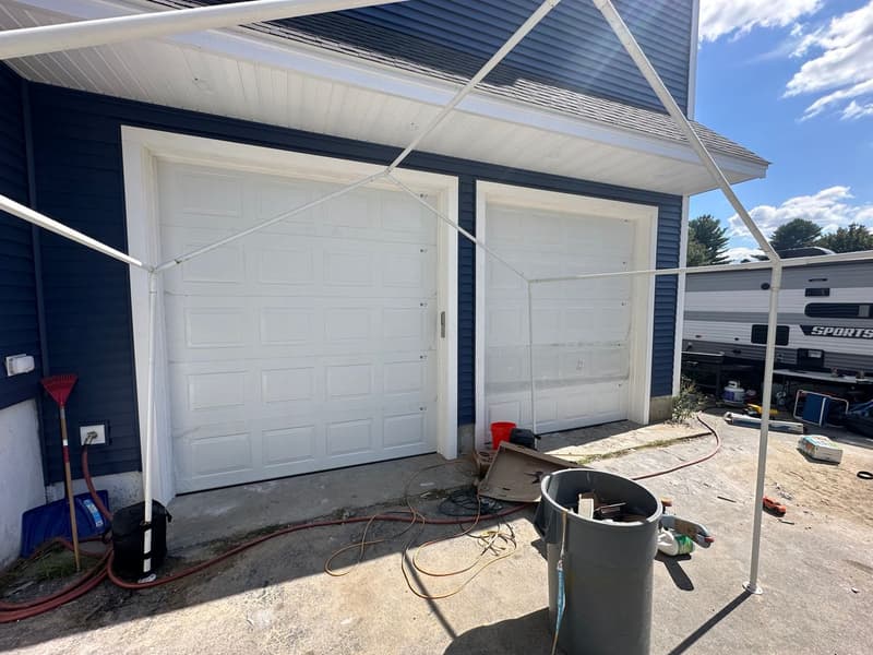 White dual flush garage doors on dark blue new construction home